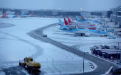 A snow plough waits to help clear snow from around aircraft after overnight snowfall caused the temporary closure of Manchester Airport in Manchester