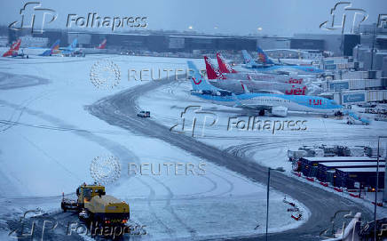 A snow plough waits to help clear snow from around aircraft after overnight snowfall caused the temporary closure of Manchester Airport in Manchester