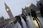 People shield from rain during morning rush-hour near Houses of Parliament, in London