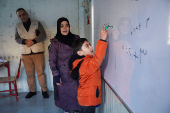 A student writes on a board inside a portable classroom in Aleppo