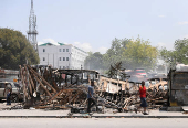 FILE PHOTO: People walk past remains of vehicles after they were set on fire by gangs, in Port-au-Prince