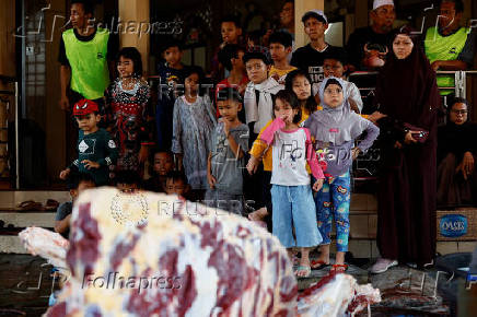Children react to a slaughtered sacrificial animal, during a ritual of Eid al-Adha celebrations in Jakarta
