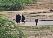 Women walk through flood water following heavy rains in Hajjah