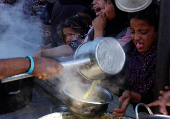 Palestinians gather to receive food cooked by a charity kitchen, amid a hunger crisis, in Khan Younis