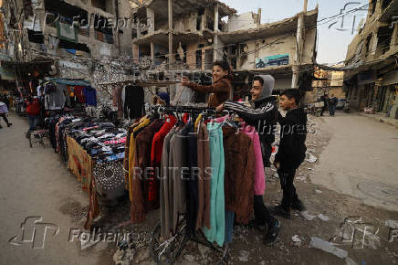 Firas, 15, a street vendor  jokes with his friends at the street market, in Douma