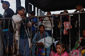 A Venezuelan, Glenda Vergara, 40, sits with her 3-year-old-daughter, as they queue to get documentation after leaving Venezuela, at the border, in Pacaraima