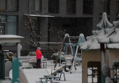 A child stands at a playground covered in snow during the first snowfall, in Kyiv