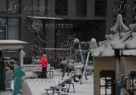 A child stands at a playground covered in snow during the first snowfall, in Kyiv