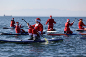 Members of the ThesSUP team wearing Santa Claus costumes paddle off the seafront of Thessaloniki