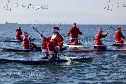 Members of the ThesSUP team wearing Santa Claus costumes paddle off the seafront of Thessaloniki