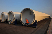 Workers prepare blades of a power-generating windmill turbine for transport, at the plant of Adani Green Energy Ltd (AGEL) at Mundra