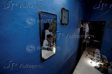 Kavita Rajkumar Pal works on her sewing machine inside her home after it was painted with solar reflective paint in a slum area in Ahmedabad