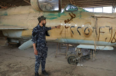 SDF member stands near a military aircraft inside Qamishli International Airport