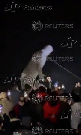 People cheer as the statue of former President of Syria Hafez al-Assad is toppled in Homs