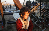 Palestinians inspect the damage at a tent camp sheltering displaced people, in Khan Younis