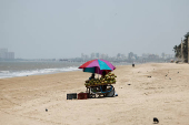 Vendor selling coconut water waits for customers at a beach on a hot day in Mumbai