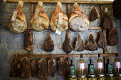Dry-cured hams and pork cheeks are hung at a grocery shop in Rome