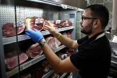 A vendor sorts dry-cured hams at a grocery shop in Rome