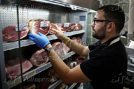 A vendor sorts dry-cured hams at a grocery shop in Rome