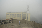 Man uses his mobile phone as he walks on the roof of a building amid smog and air pollution in Lahore