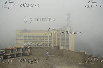 Man uses his mobile phone as he walks on the roof of a building amid smog and air pollution in Lahore