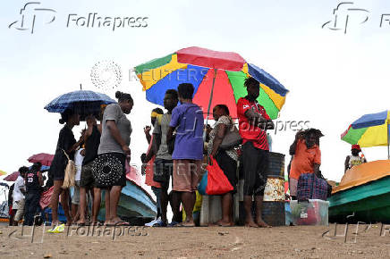 Voters and their families shelter from the rain while waiting to board small boats to vote in their provinces ahead of the election, in the capital Honiara