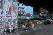 People sit next to torn election posters at a street in Dematagoda, Colombo