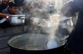 Palestinians gather to receive food cooked by a charity kitchen, amid a hunger crisis, in Khan Younis