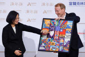 Taiwanese President Tsai points at the gift given by AmCham Chairman Silver at an American Chamber of Commerce event in Taipei