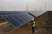 A technician checks the movement of an Automated cleaning brush installed over solar panels in Khavda Renewable Energy Park of Adani Green Energy Ltd (AGEL), in Khavda