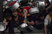 Displaced Palestinians collect donated food in Khan Yunis, southern Gaza