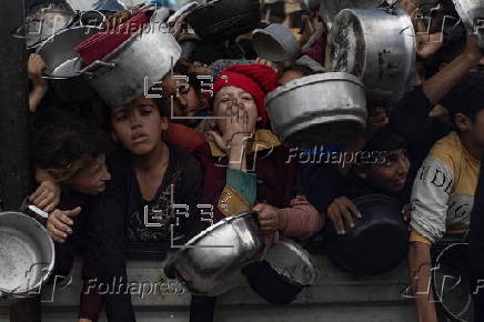 Displaced Palestinians collect donated food in Khan Yunis, southern Gaza