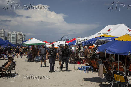 Fiscais so acompanhados por guardas-civis e PMs durante ao na praia, em Guaruj