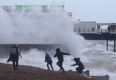 People run on the beach near Palace Pier as Storm Nelson arrives at Brighton