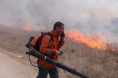 A man attempts to extinguish flames following a rocket attack from Lebanon, in the Israeli-occupied Golan Heights