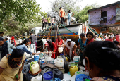 Residents use pipes to fill their containers with drinking water from a water tanker