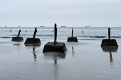 Anti-landing barricades are pictured on a beach as vessels out in the water navigate past Kinmen Island