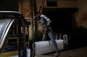A workers loads an ice block into a vehicle at a factory on a hot summer day in Karnal