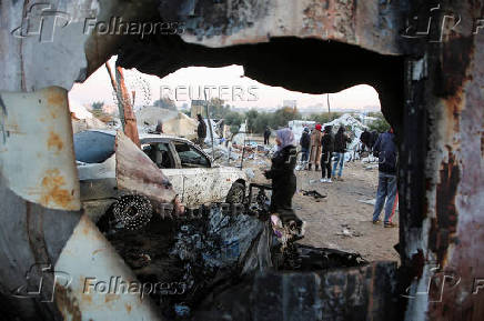 Palestinians inspect the damage at a tent camp sheltering displaced people, in Khan Younis