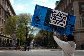 A demonstrator holds a sign across from the Columbia University campus with a student protest encampment in support of Palestinians, in New York City