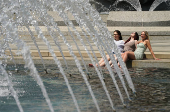 Women dip their feet in the water at the World War II Memorial  in Washington