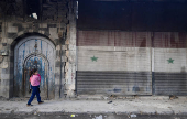 A girl holds her sibling along the street, in Douma