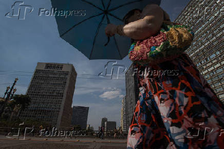 Mulher usa sombrinha para se proteger do sol no viaduto do Ch, no centro de SP
