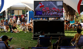 People watch a screen displaying the Opening Ceremony of the Paris 2024 Olympics, in Saint-Etienne