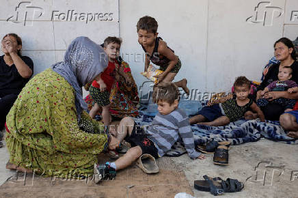 Displaced from southern Beirut suburbs, Asmaa Kenji helps her son put on his shoes, as they live on the streets of central Beirut