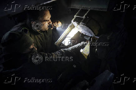 Servicemen prepare a howitzer to fire towards Russian troops at a frontline near the town of Chasiv Yar