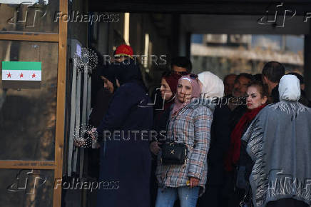 People wait in line in front of ATM, in Damascus