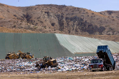 FILE PHOTO: Workers use heavy machinery to move trash and waste at the Frank R. Bowerman landfill in California