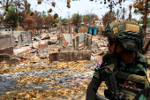 A soldier from the Karen National Liberation Army (KNLA) patrols, next to an area destroyed by Myanmar's airstrike in Myawaddy, the Thailand-Myanmar border town under the control of a coalition of rebel forces led by the Karen National Union