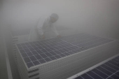 A technician checks a connector of Photovoltaic Modules at the plant of Adani Green Energy Ltd (AGEL) in Mundra